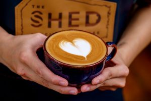 A barista holds a beautiful specialty coffee with a heart-shaped latte art at The Shed Coffee in Charlottetown.